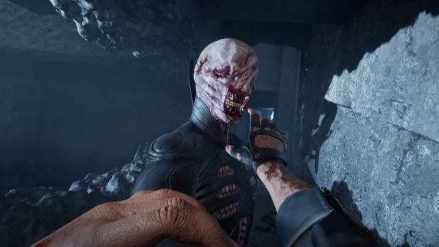 A Cenobite's pale hand and hooked face emerging from shadow in the Labyrinth of Clive Barker's Hellraiser: Revival.
